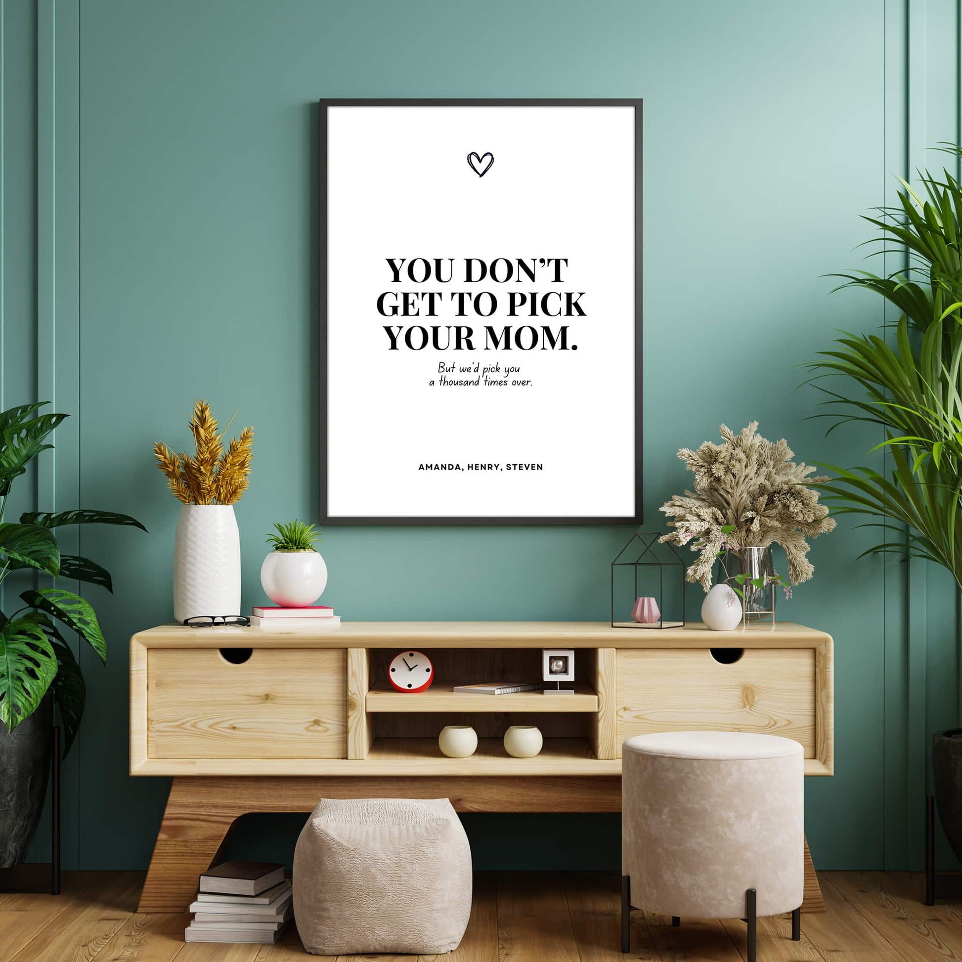 A black and white poster with the quote ‘You don’t get to pick your dad. But we’d pick you a thousand times over,’ personalized with children’s names and a small heart symbol above, hanging on the wall of a cozy living room.